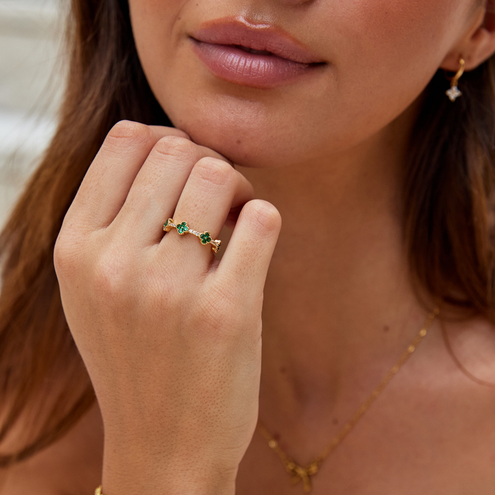 Annika – Anello placcato oro con dettagli floreali e un elemento in smeraldo.